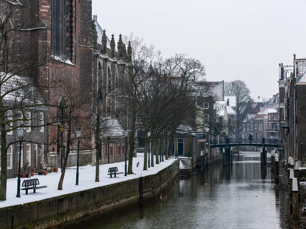 A snowy scene in historic Dordrecht in the Netherlands. Dutch architecture old houses and homes on the canal.